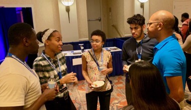 Students chat with a faculty member at a conference