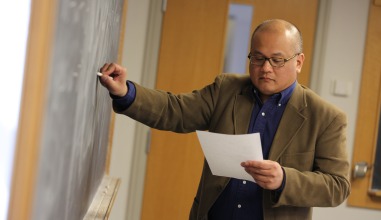 Professor Angelo Mercado teaches at a whiteboard.