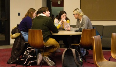 A group of students sit on a table, seemingly discussing questions in low voices