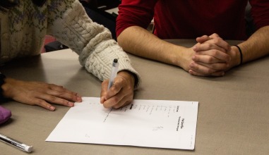 A hand writes on a blank answer sheet