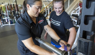 A coach helps an athlete lift with proper form