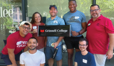 Alumni gathered around a sign that reads Grinnell College 