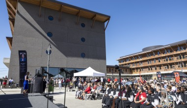 A crowd gathers in the street near Renfrow Hall for the building dedication under a brilliant blue sky