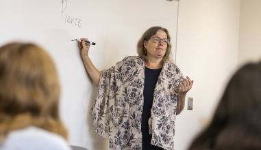 A woman professor writes on a white board