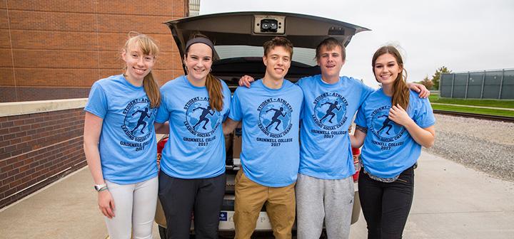 5 students stand next to a car loaded with donations for hurricane relief