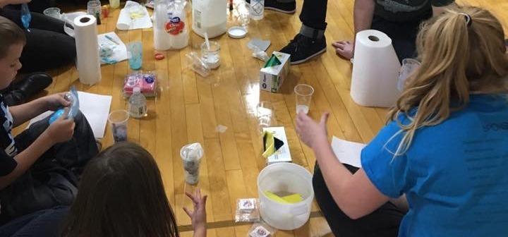 Children sit on the floor and get their hands dirty creating slime.