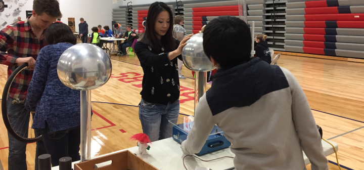 An onlooker touches the ball at the top of the Van de Graaff generator to feel the static electricity charge.