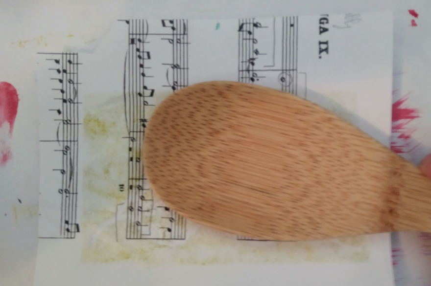 A wooden spoon pressing on a piece of paper
