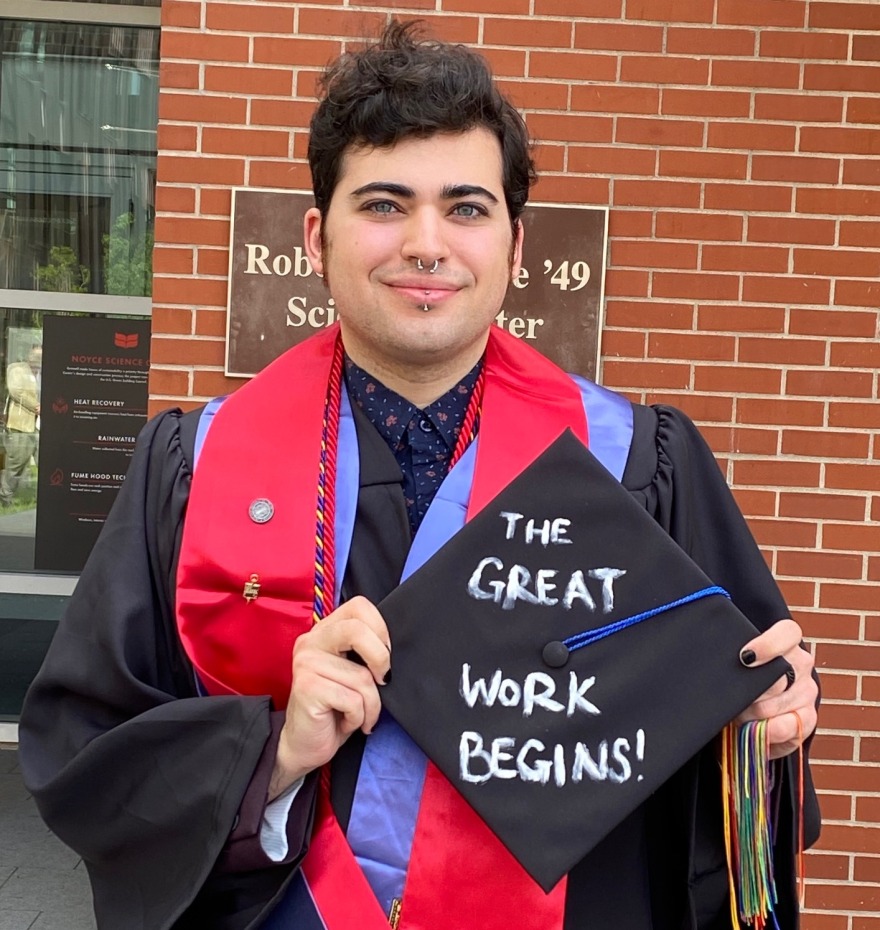 Peppers holds graduation cap which reads, "The Great Work Begins!"