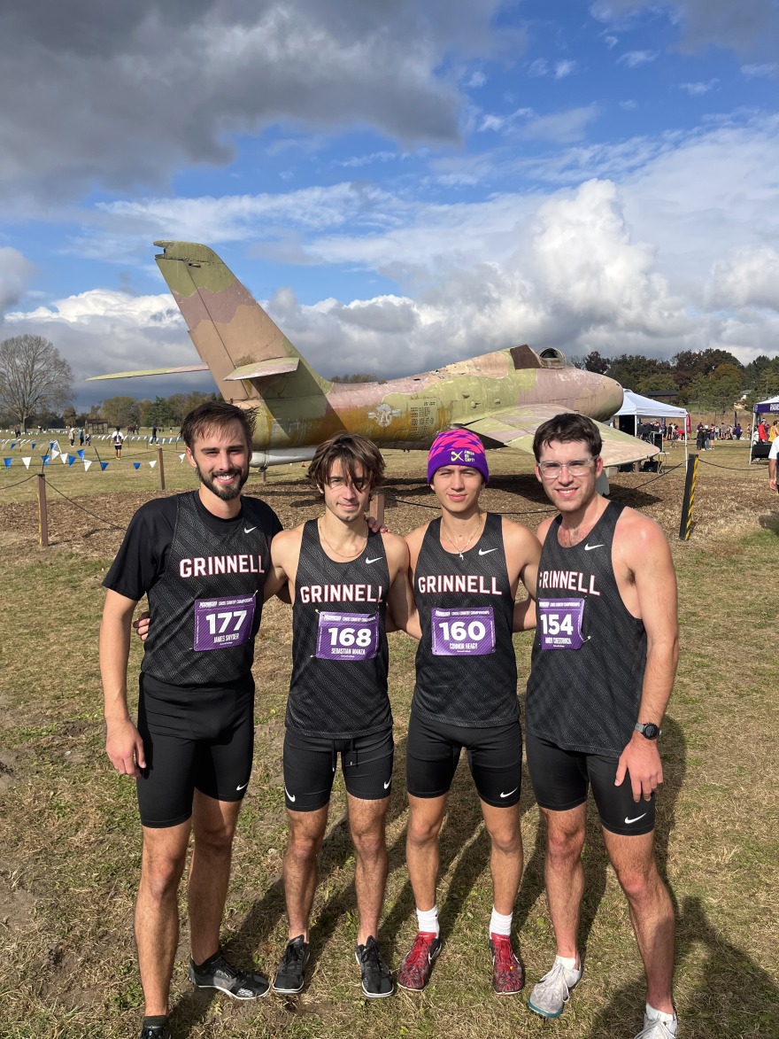 James and three cross country teammates pose in front of a vintage airplane