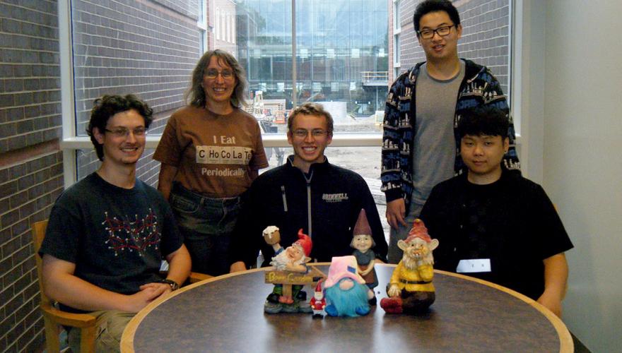 Four students and their faculty mentor pose with some gnome statues. 