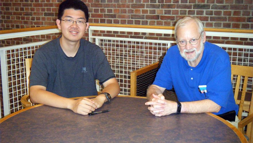 A student and his faculty mentor at a round table.