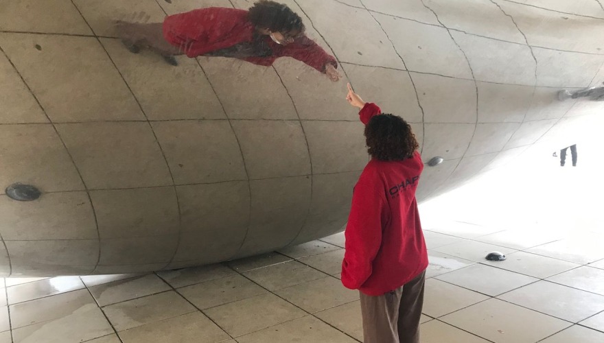 A student points at her reflection in Anish Kapoor's Cloud Gate sculpture (AKA The Bean) in Chicago's Millennium Park