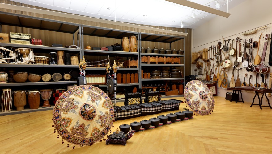 a variety of musical instruments are stored on shelves and walls with more on display in the middle of the room