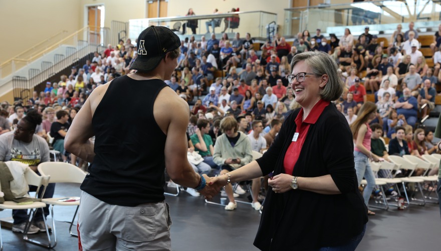 President Anne F. Harris greets a first-year student during a welcome ceremony Aug. 17 where the class of 2027 received silver medallions to commemorate James J. Hill’s first gift to Grinnell in 1846.  