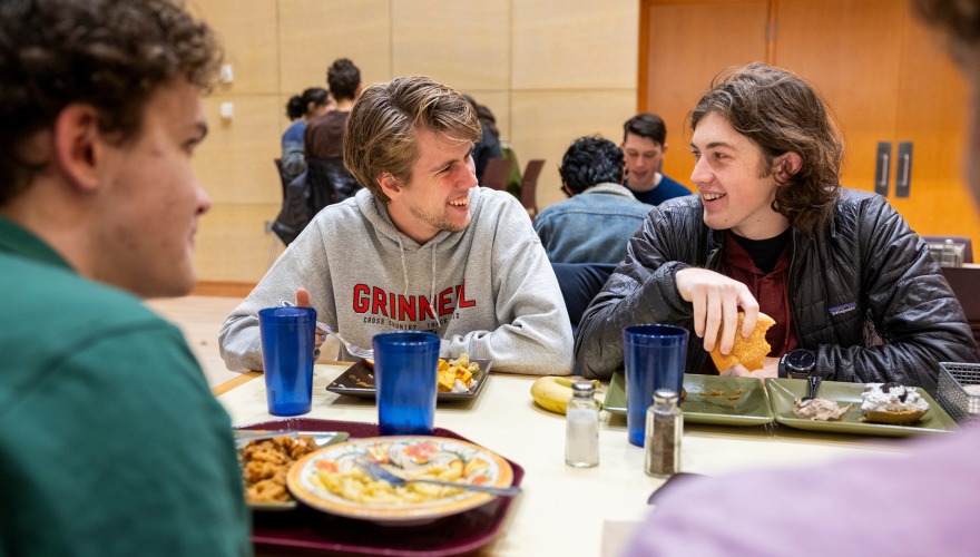 Brian and his friends laugh and enjoy dinner in the dining hall