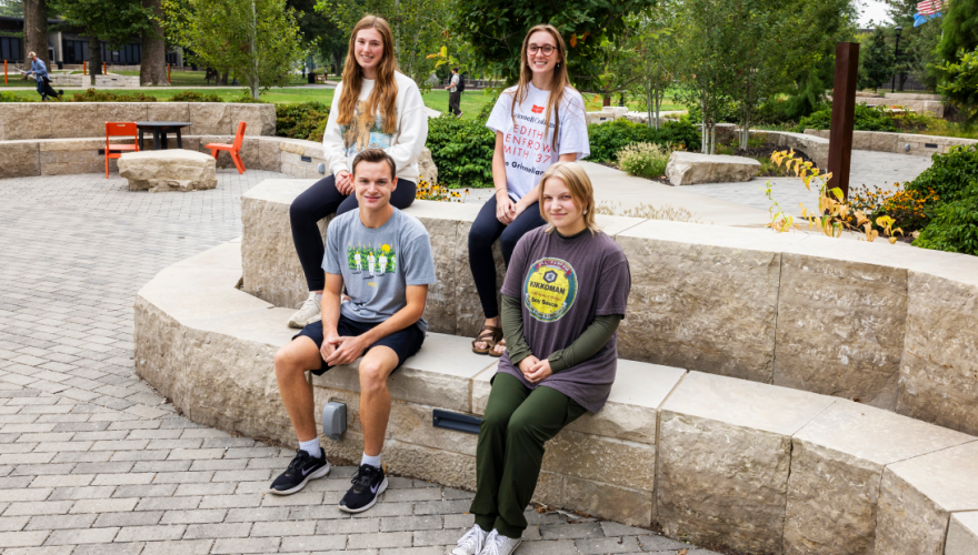 four first year students sitting on stone benches in Kington Plaza