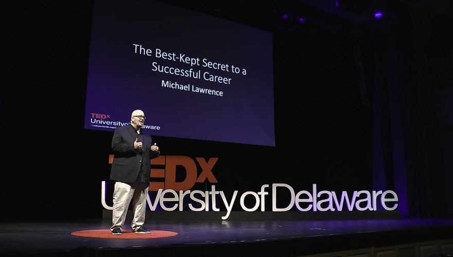 Lawrence speaks in front of a presentation screen that reads, "The Best-Kept Secret to a Successful Career."