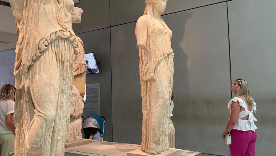 A young woman admires classical Greek statuary.
