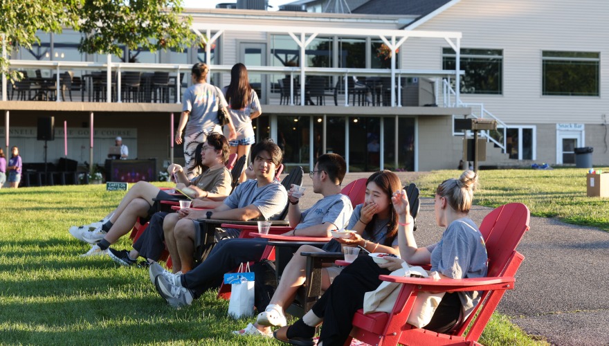 Students sitting in red and black Adirondack chairs