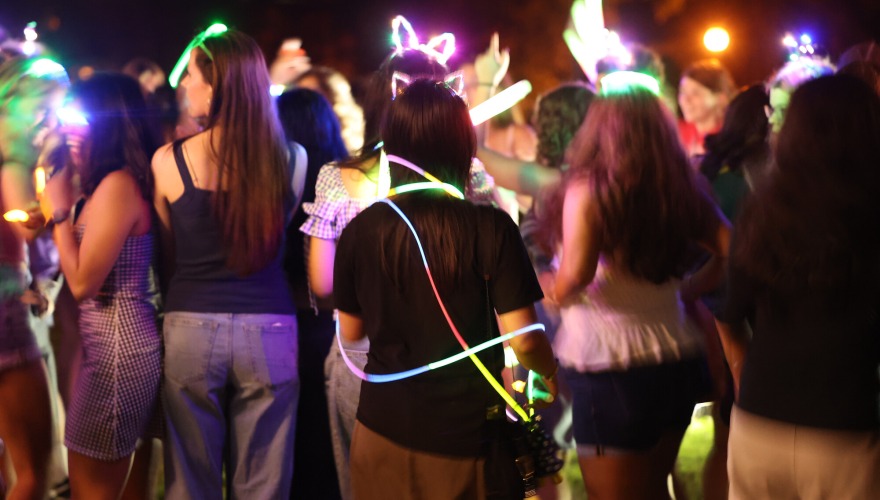 A group of students wear lighted accessories and glow sticks.