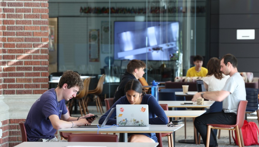 Students sit in pairs at small tables.