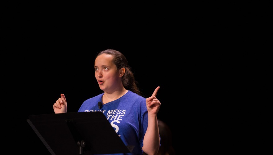 Emma Haddock ’27 wearing a blue shirt and pointing up with both hands