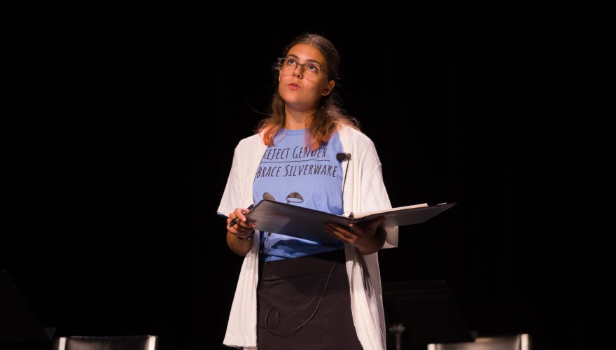 Hazel Saydak ’28 holding a black binder and wearing a blue shirt under a white cardigan