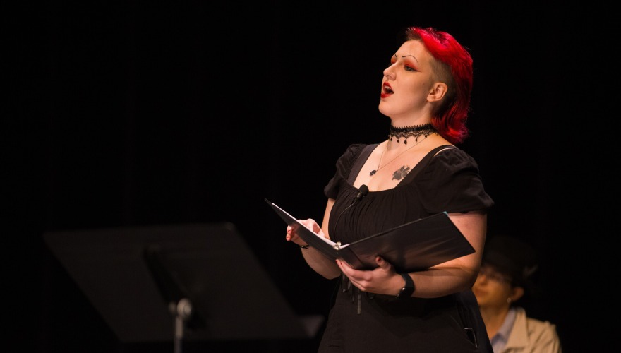 Noelle Buehrer ’26 with vibrant red hair wearing a black dress and holding a black binder