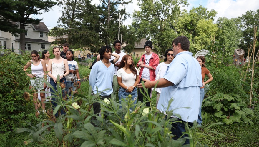 A group of students stand with Chris Bair in the college garden.