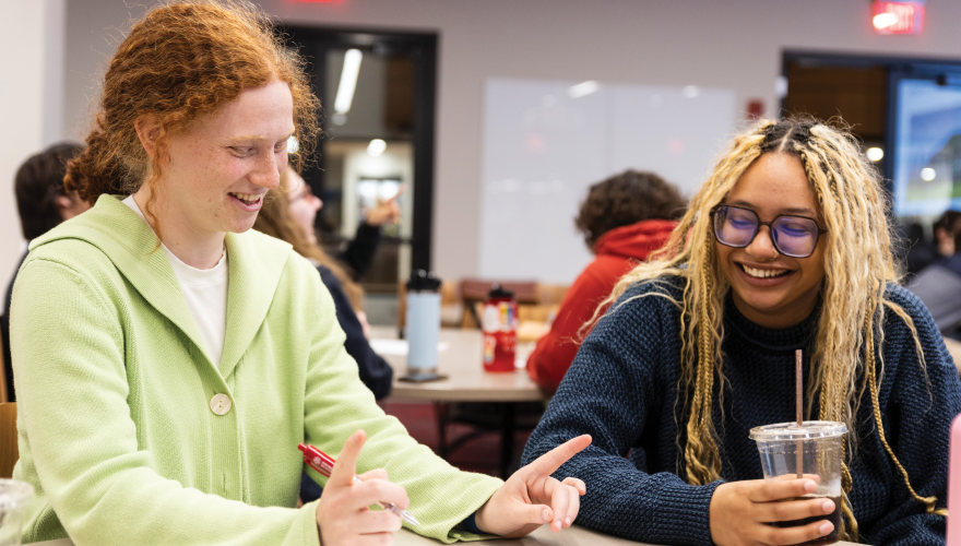 Maddie and a friend laugh together at a table