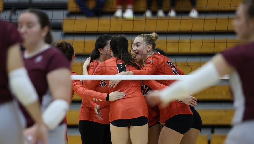 Grinnell volleyball players stand in a huddle