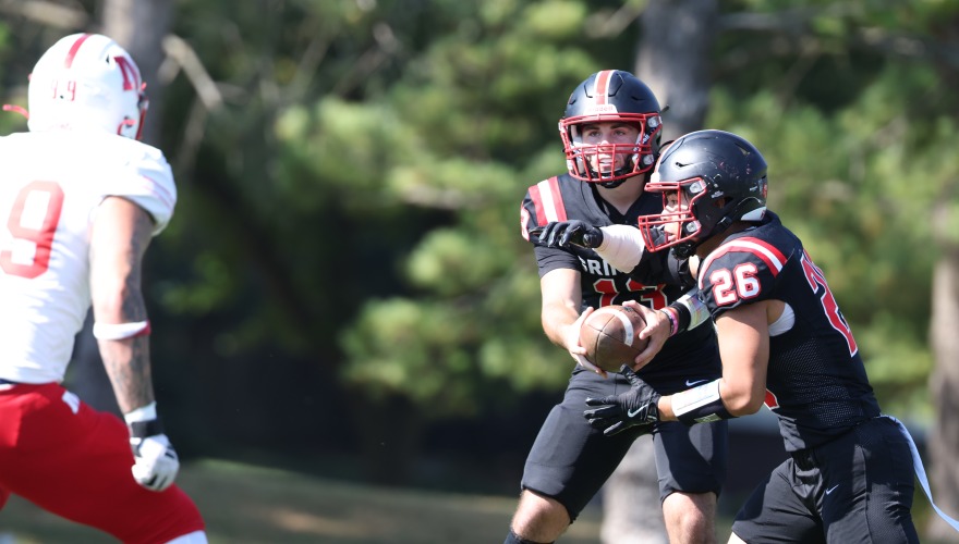 Two football players in black facing toward one in white