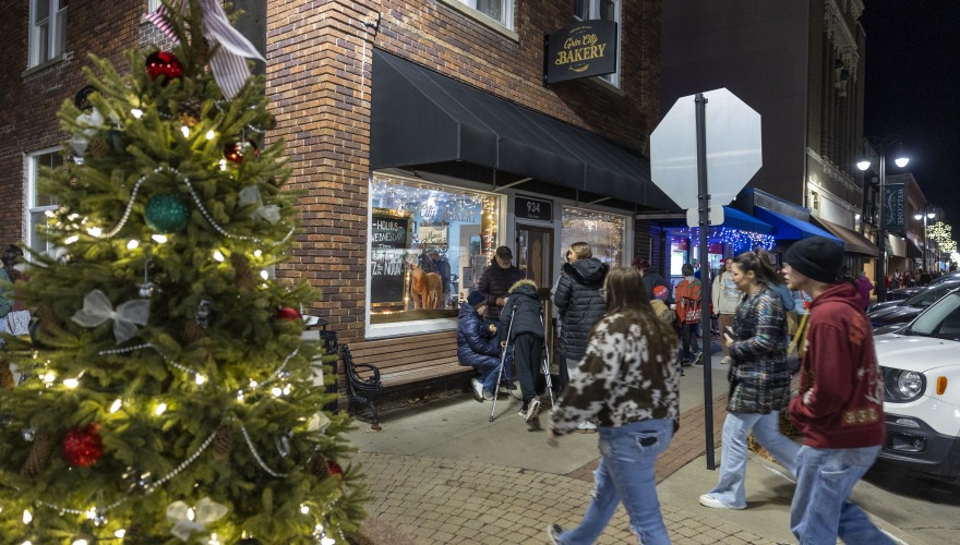 People walking into donut shop with christmas tree in photo