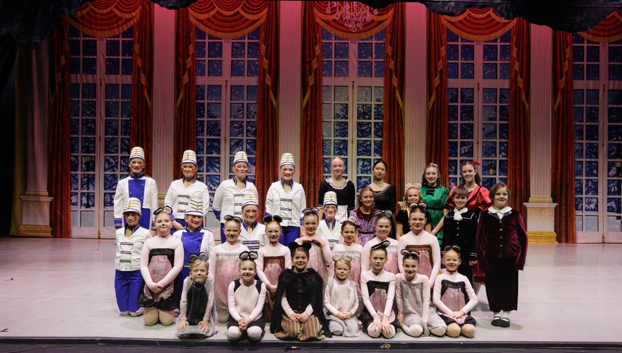 children standing on stage in costumes from the Nutcracker for a photo