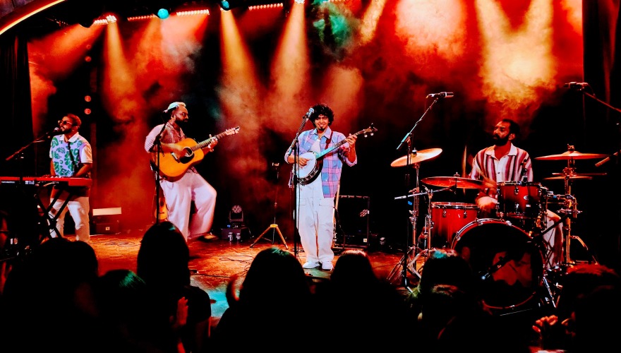 A band performs onstage with bright lights