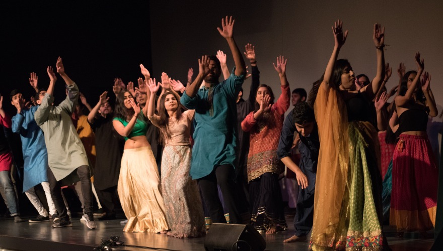 Students in brightly colored clothing dance in celebration of Diwali
