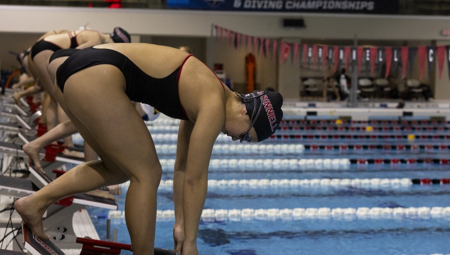 Swimmers lined up on starting blocks, ready to dive into the pool