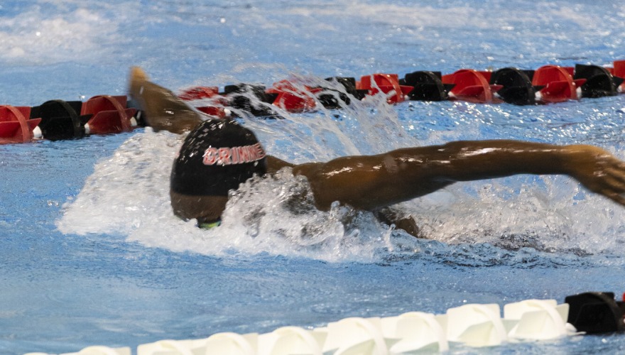 A swimmer in black in the water, swimming butterfly