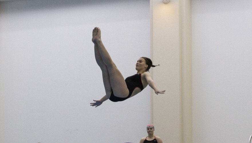 A diver flipping backwards above two diving boards and into a pool