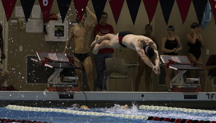A swimmer dives off the starting block into the pool