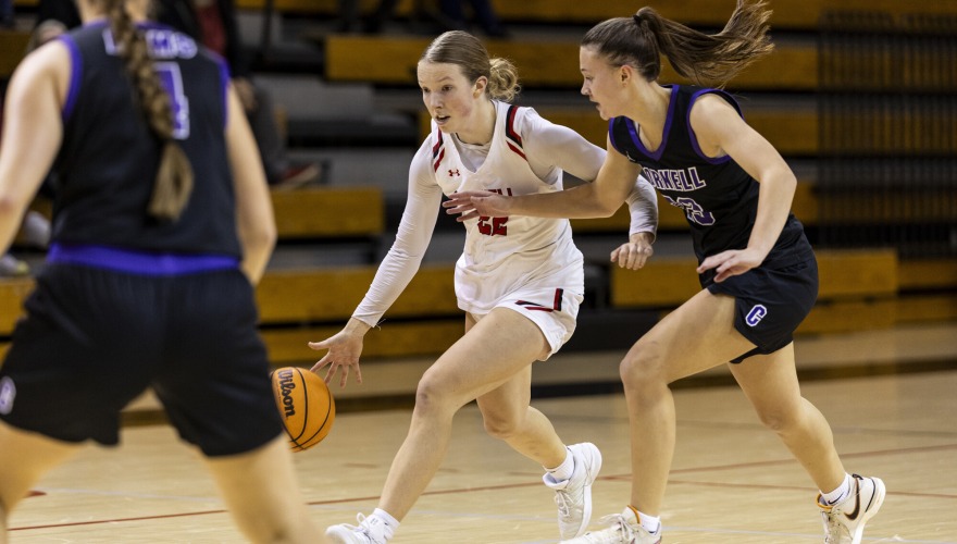 Women's basketball player dribbles up the court while an opponent defends her