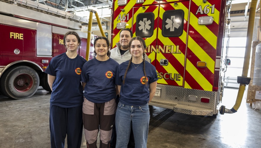 three students and chief in front of ambulance 