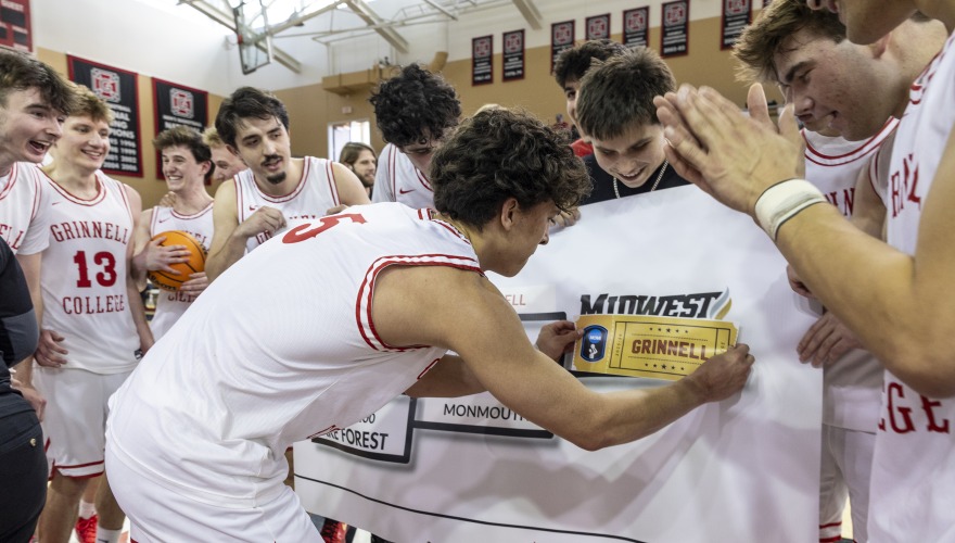 Men's basketball player places "champion" logo onto banner