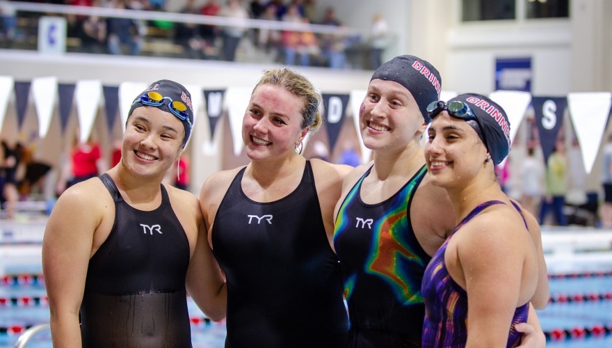 Four women's swim team members pose for a photo after a race