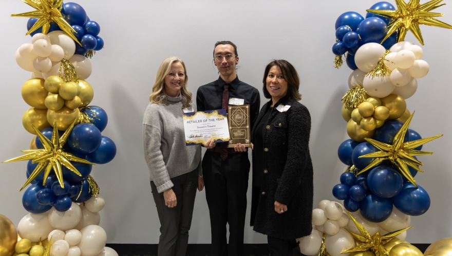 3 people standing with award and balloon on each side
