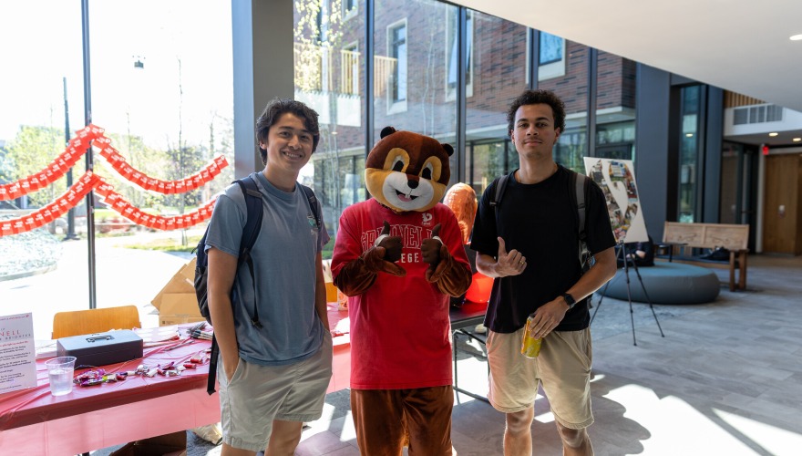 2 guys standing with a squirrel mascot
