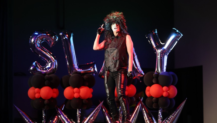 A performer on stage during Drag Show with balloons that say SLAY in the background.