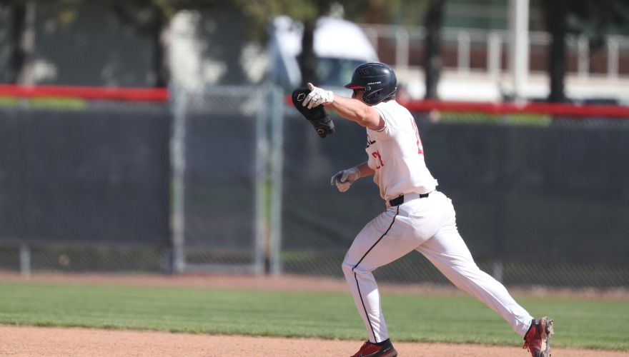 Base runner rounding first with his fist raised in celebration.