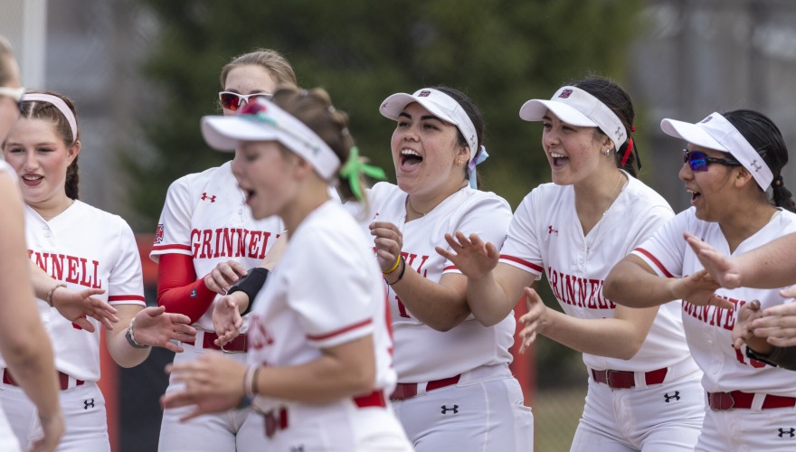 Members of the softball team cheer as they prepare for the game to begin.
